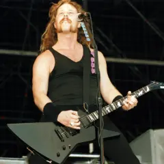 James Hetfield z Metalliki gra na czarnej gitarze na scenie.