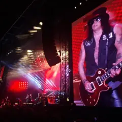 Slash z Guns N' Roses gra na gitarze na wielkim ekranie podczas koncertu w Warszawie.