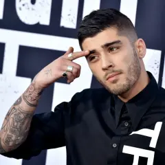 Zayn Malik, były członek One Direction, z tatuażami na ramieniu i palcami ozdobionymi pierścionkami, dotyka czoła.