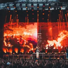 Koncert na festiwalu z ognistą scenografią i tłumem widzów.