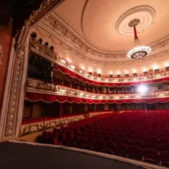 Wnętrze teatru z czerwonymi fotelami i lożami, gotowe na wspaniałe arie operowe.