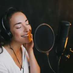 Kobieta w słuchawkach śpiewa do mikrofonu. Czy to magia autotune co to?