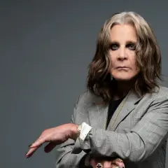 Ozzy Osbourne w szarej marynarce, z charakterystycznym makijażem oczu. Ikona rocka, której ozzy osbourne utwory wciąż inspirują.