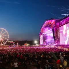 Koncert na Pol'and'Rock Festival z wielkim tłumem, sceną i diabelskim młynem w tle.