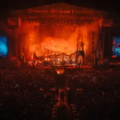 Koncert na Orange Warsaw Festival. Tłum ludzi pod sceną, na której trwa widowiskowe show z efektami pirotechnicznymi.