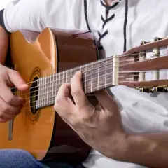 Dłonie grają na gitarze klasycznej, tworząc akordy. To może być najłatwiejsza piosenka na gitarze, którą właśnie ćwiczysz.