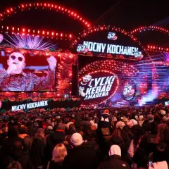 Koncert WOŚP 2026: tłumy ludzi pod sceną, na ekranach artyści, czerwone światła i serca WOŚP.