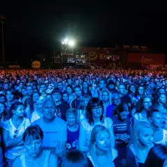 Tłum ludzi na koncercie, oświetlony niebieskim i pomarańczowym światłem. W tle widać banery z logo Energa i Lotos. To prawdziwa inwazja mocy, jak na koncercie Scorpions!