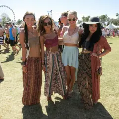 Cztery młode kobiety w letnich strojach pozują na tle festiwalu Coachella.