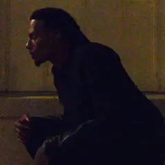 Playboi Carti w Polsce, siedzi w mroku, czekając na coś.