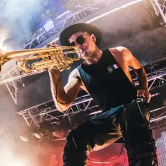 Timmy Trumpet gra na trąbce na scenie podczas koncertu.
