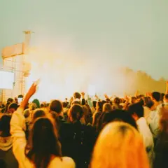 Tłum ludzi na koncercie, uniesione ręce, scena z oświetleniem. Tak wyglądają juwenalia, czyli święto studentów.