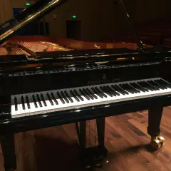 Czarny fortepian Steinway & Sons z otwartą klapą, na drewnianej scenie.