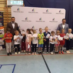 Dzieci z dyplomami i medalami stoją przed banerem "Małopolska".