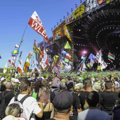 Tłum ludzi na festiwalu muzycznym z flagami i sceną w tle.