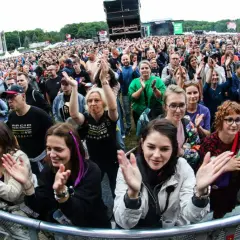 Tłum na koncercie w Poznaniu, fani klaszczą i cieszą się występem. Widoczny fragment sceny i festiwalowej atmosfery.