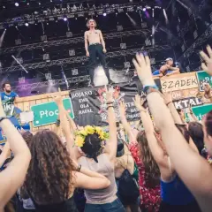 Energiczny tłum na czaplinek festiwal, z rękami w górze, podczas koncertu. Wokalista na scenie, fani szaleją.