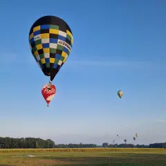Balony unoszą się na niebie, przypominając o znaczeniu 99 luftballons. W oddali widać więcej balonów.