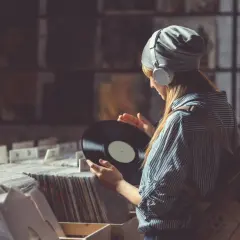 Dziewczyna w słuchawkach przegląda płyty winylowe w sklepie. Szuka idealnego EP, co to za muzyka?