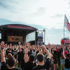 Tłum ludzi z rękami w górze na festiwalu Rockowizna przed sceną.