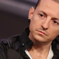 Chester Bennington z Linkin Park, z charakterystycznymi czarnymi tunelami w uszach, w czarnej kurtce.