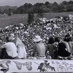 Widok z góry na tłum ludzi na festiwalu Woodstock '69, z kilkoma osobami siedzącymi na ozdobionej ciężarówce.