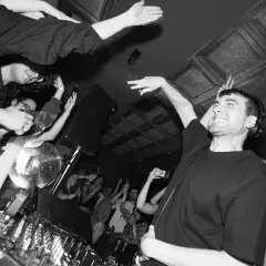 Energiczny DJ Fred Again w Polsce, tłum szaleje przy muzyce, dyskotekowa kula błyszczy.