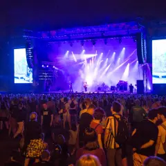 Tłum ludzi na OFF Festivalu, podziwiający koncert na oświetlonej scenie.