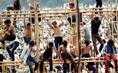Ludzie wspinający się na żółtą konstrukcję podczas festiwalu Woodstock 1969.
