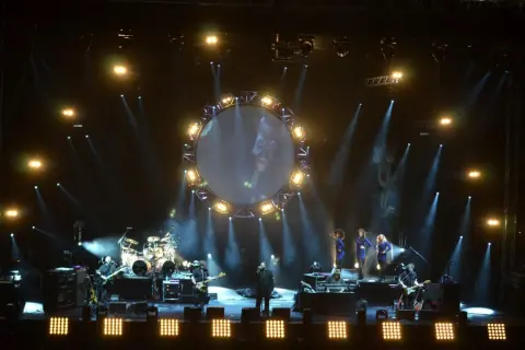 Koncert The Australian Pink Floyd Show z okrągłym ekranem i muzykami na scenie.