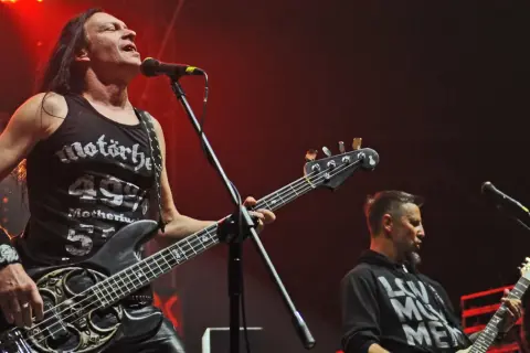 Dwóch muzyków Acid Drinkers grających na gitarach basowych na scenie.