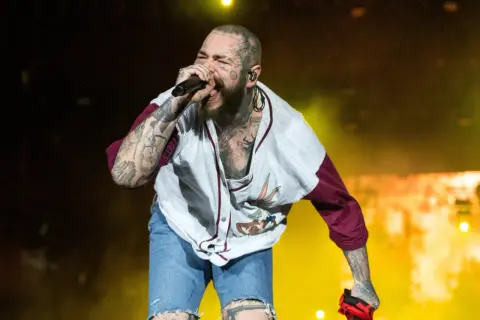 Post Malone śpiewa na koncercie w koszulce z Królikiem Bugsem i dżinsowych szortach.