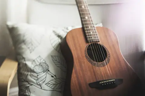 Akustyczna gitara obok poduszki z liśćmi. Idealna do grania harcerskie piosenki chwyty przy ognisku.