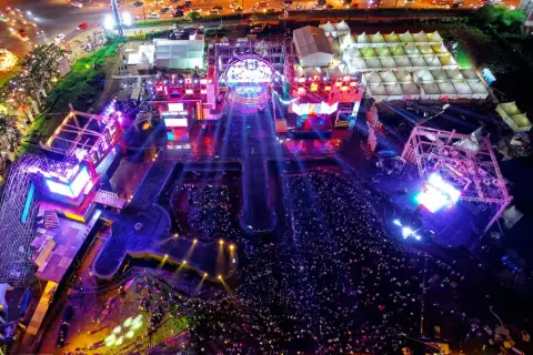 Widok z lotu ptaka na nocny koncert z tłumem i oświetloną sceną.