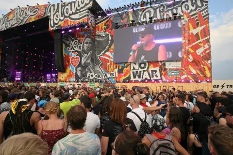 Tłum ludzi na koncercie Pol'and'Rock przed sceną z wielkim ekranem i grafikami.