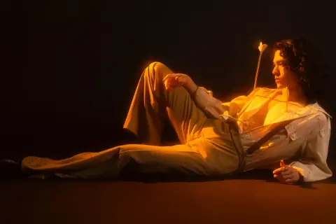 Conan Gray w stylizacji inspirowanej romantyzmem, z dwoma strzałami w klatce piersiowej, jakby po koncercie.
