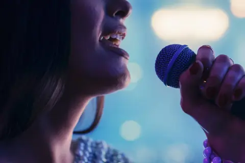 Kobieta śpiewa do mikrofonu. Czy to playback? Nie, czuć emocje w jej głosie.