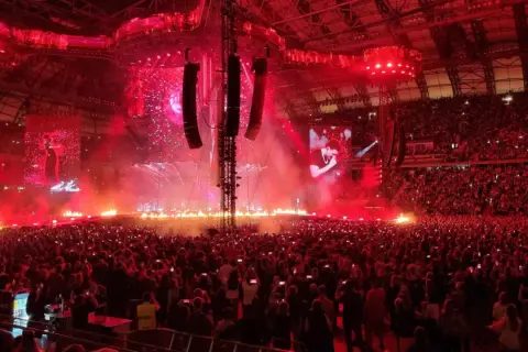 Koncert Dawida Podsiadło w Poznaniu: scena z ogniem, tłum ludzi i ekrany z artystą.