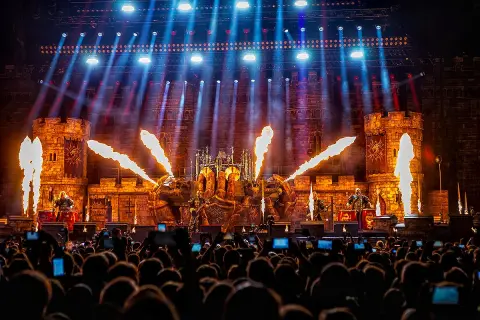 Koncert Sabaton z pirotechniką i scenografią zamku, widziany z perspektywy publiczności.