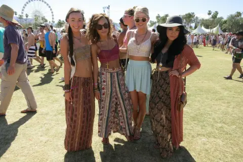 Cztery młode kobiety w letnich strojach pozują na tle festiwalu Coachella.