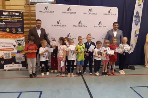 Dzieci z dyplomami i medalami stoją przed banerem "Małopolska".