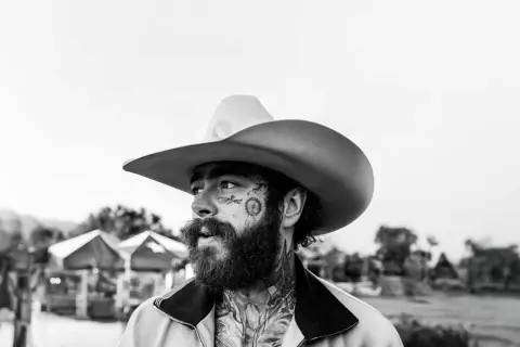 Post Malone w kowbojskim kapeluszu, z tatuażami na twarzy, gotowy na swój kolejny koncert.