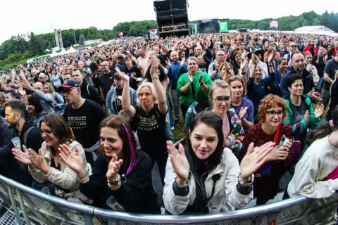 Tłum na koncercie w Poznaniu, fani klaszczą i cieszą się występem. Widoczny fragment sceny i festiwalowej atmosfery.