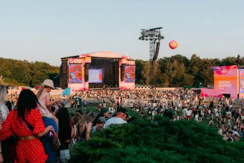 Tłum ludzi na festiwalu Bittersweet, scena w tle, różowe dekoracje i balon unoszący się na niebie.