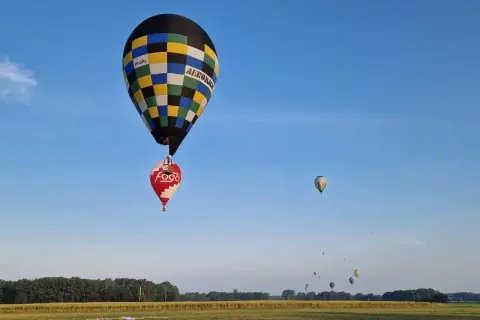 Balony unoszą się na niebie, przypominając o znaczeniu 99 luftballons. W oddali widać więcej balonów.