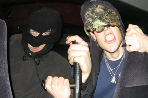 Dwóch mężczyzn w kominiarkach, jeden trzyma tonfę. Ich styl to czysty tonfa rap.