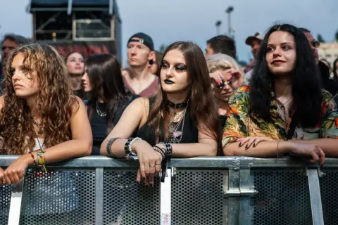 Młode kobiety z bransoletkami i naszyjnikami, czekające na koncert podczas krakowskiego festiwalu muzycznego.