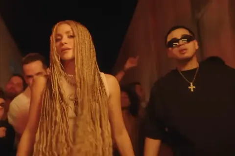 Shakira z warkoczami i raperem w okularach przeciwsłonecznych, jakby na planie teledysku "El Jefe".