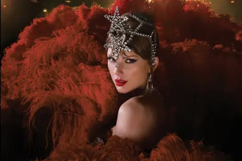 Taylor Swift w teatralnej kreacji z piór i biżuterii. Zastanawiasz się, ile piosenek ma Taylor Swift?