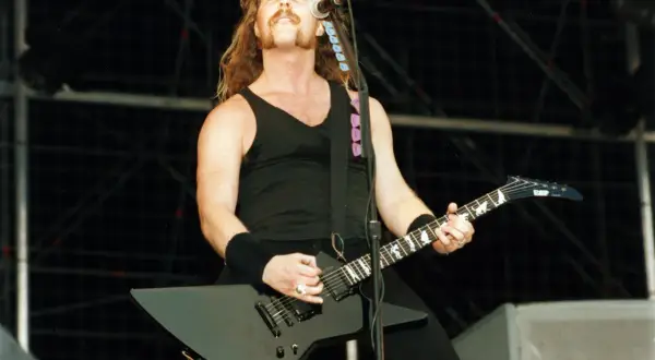 James Hetfield z Metalliki gra na czarnej gitarze na scenie.